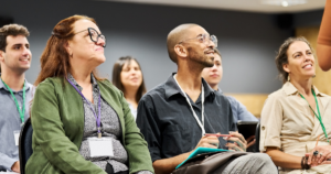 A group of higher education professionals listening to a speaker at a conference.